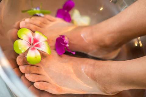 Pies en un baño de agua tibia con flores de frangipani